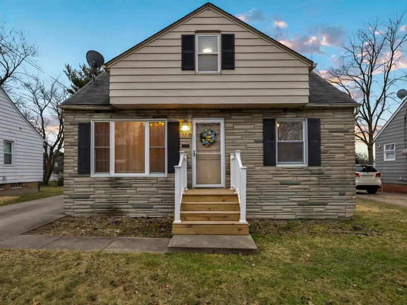 Stone and siding cape cod with black shutters and a lit front porch