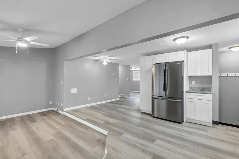 Living and dining space open to the kitchen, with the refrigerator and cabinets beyond