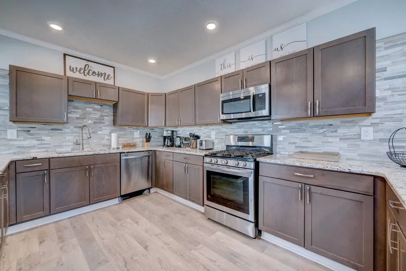 Kitchen corner with a stainless gas range, dishwasher and tiled backsplash