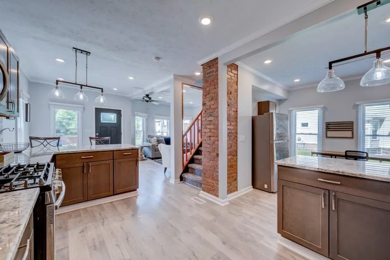 Open floor looking from the kitchen past a brick column to the living room and stairs