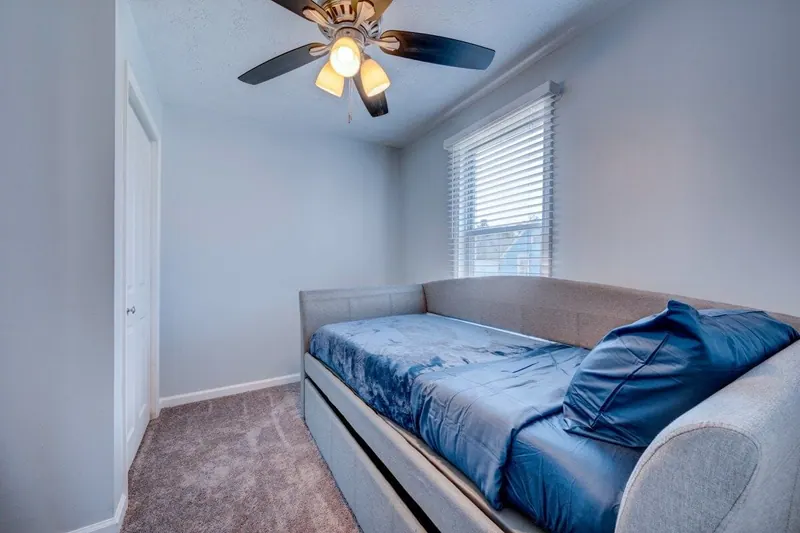 Bedroom with a twin bed in blue bedding and a ceiling fan