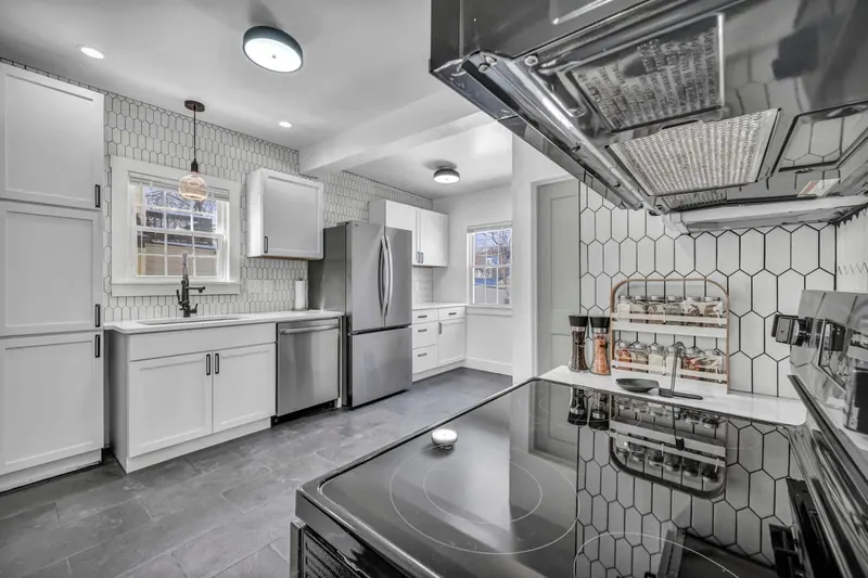 Kitchen with white cabinets, a hexagon tile backsplash and a stainless refrigerator