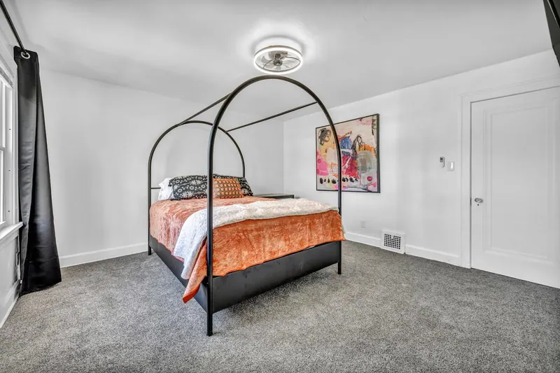 Bedroom with a black canopy bed and a window onto the street